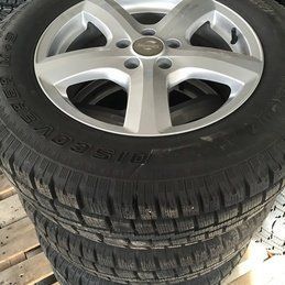 Une pile de pneus et de roues sont superposées sur une palette en bois.