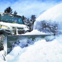 Un chasse-neige souffle la neige du bord d'une route.