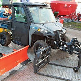 Un véhicule utilitaire auquel est fixé un chasse-neige est stationné sur le bord de la route.