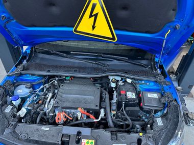 Un mécanicien travaille sur un moteur de voiture avec un multimètre.