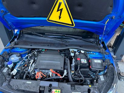 Un mécanicien travaille sur un moteur de voiture avec un multimètre.