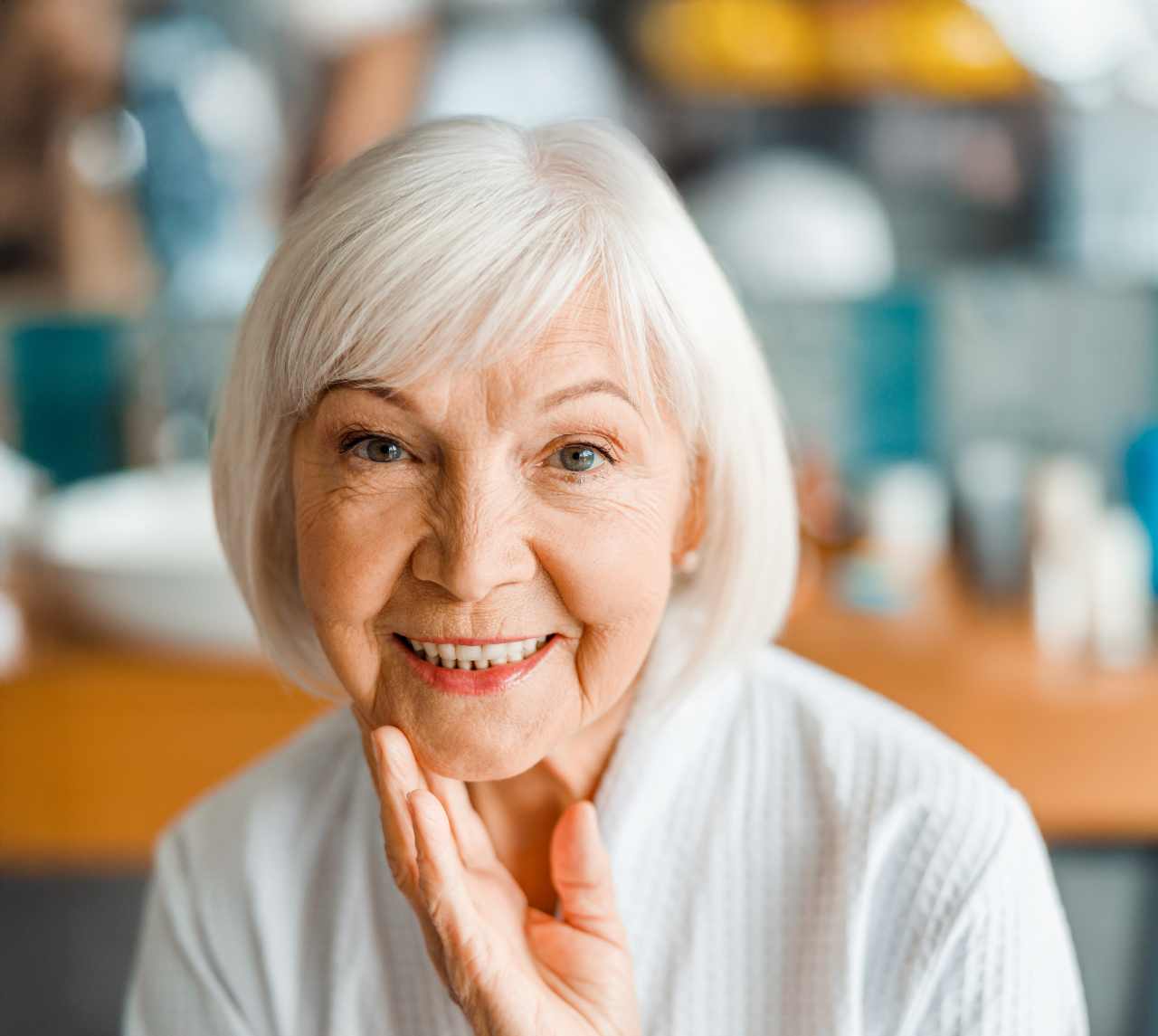 A person with a bright, wide smile holds both hands to their cheeks.