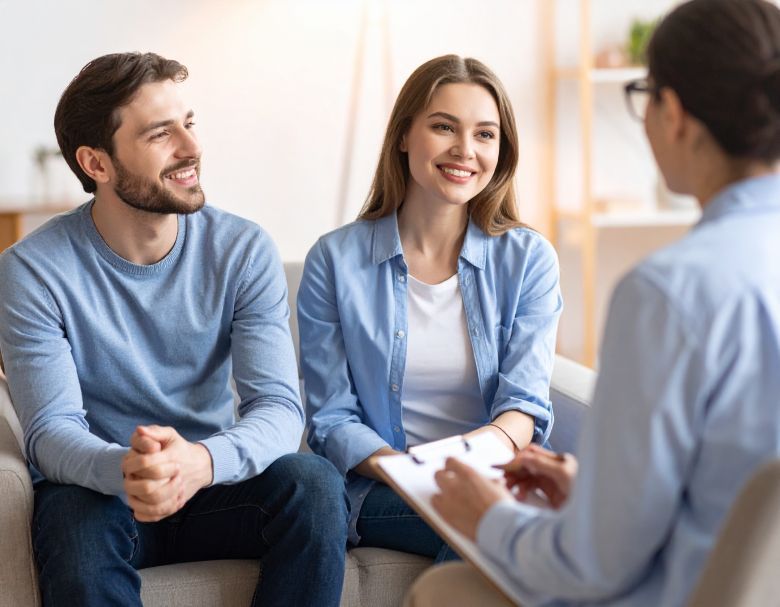 Couple smiling at a therapist, sitting in an office setting. They are in counseling.