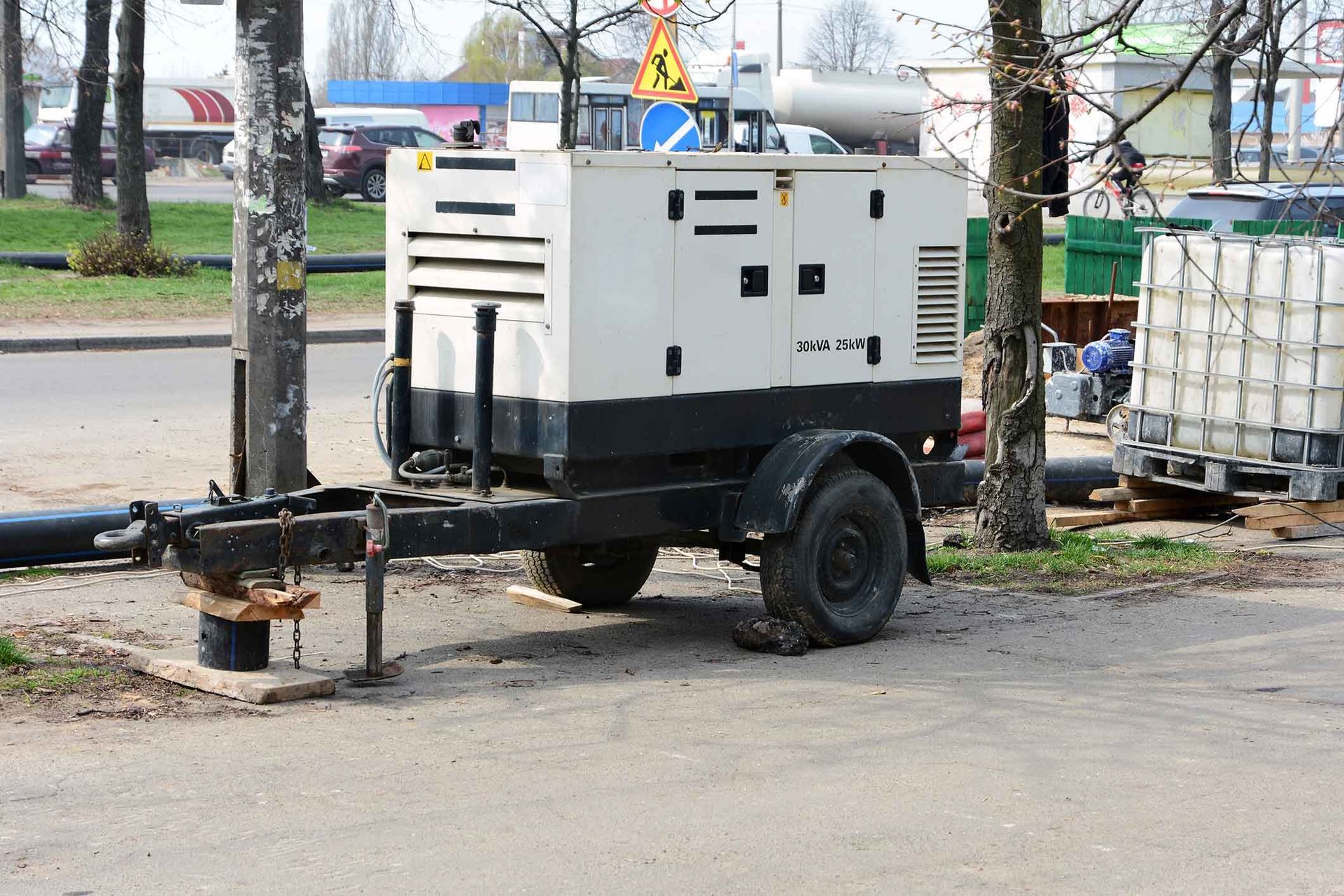 White and black generator on a trailer parked beside a road.