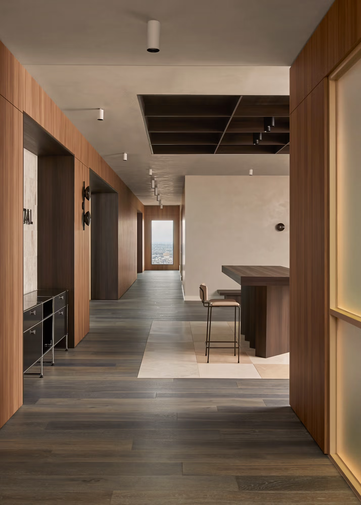 Modern hallway with wood accents, gray flooring, and a bar counter by a bright window.