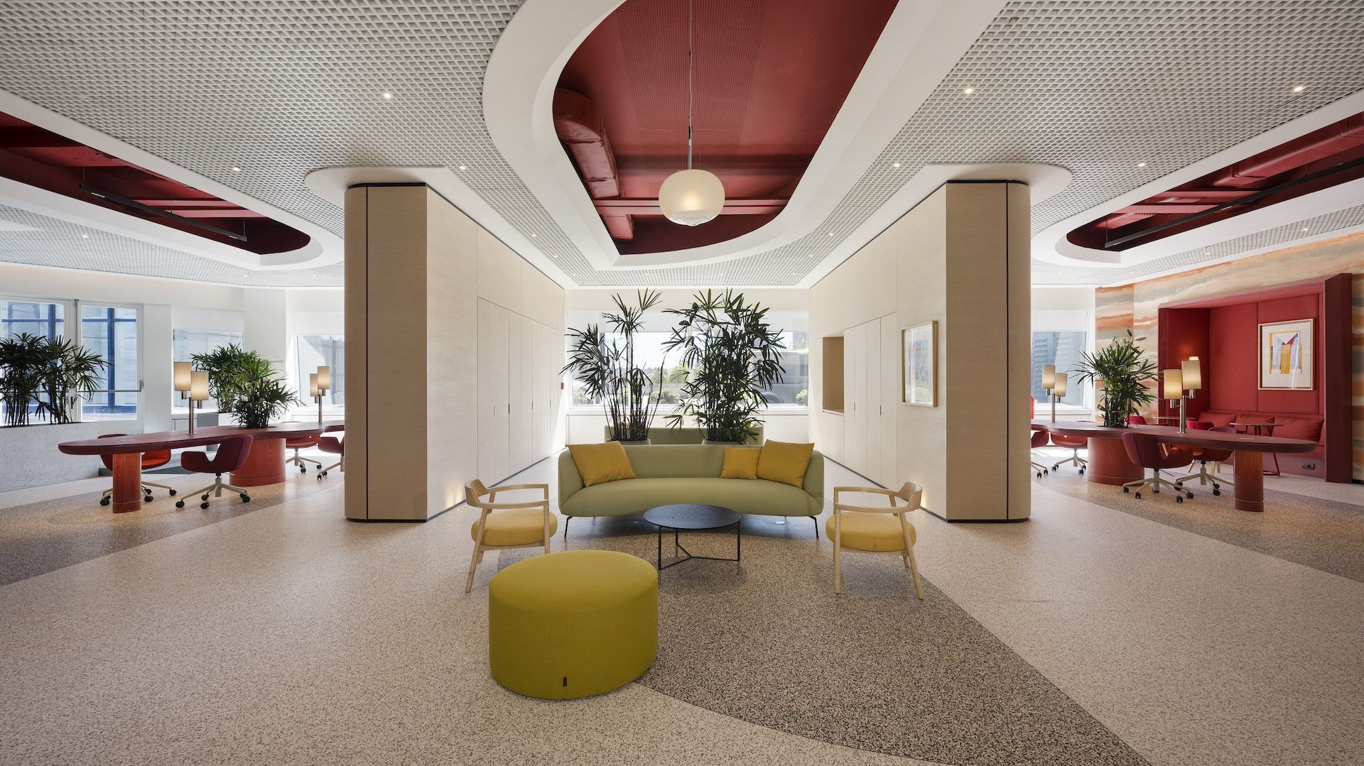 Modern lobby with patterned ceiling, central seating, and warm red and beige accents