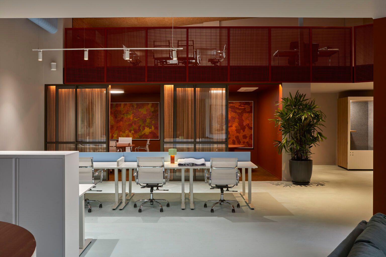 Modern open office kitchen with tables, chairs, wood cabinets, and a large potted plant