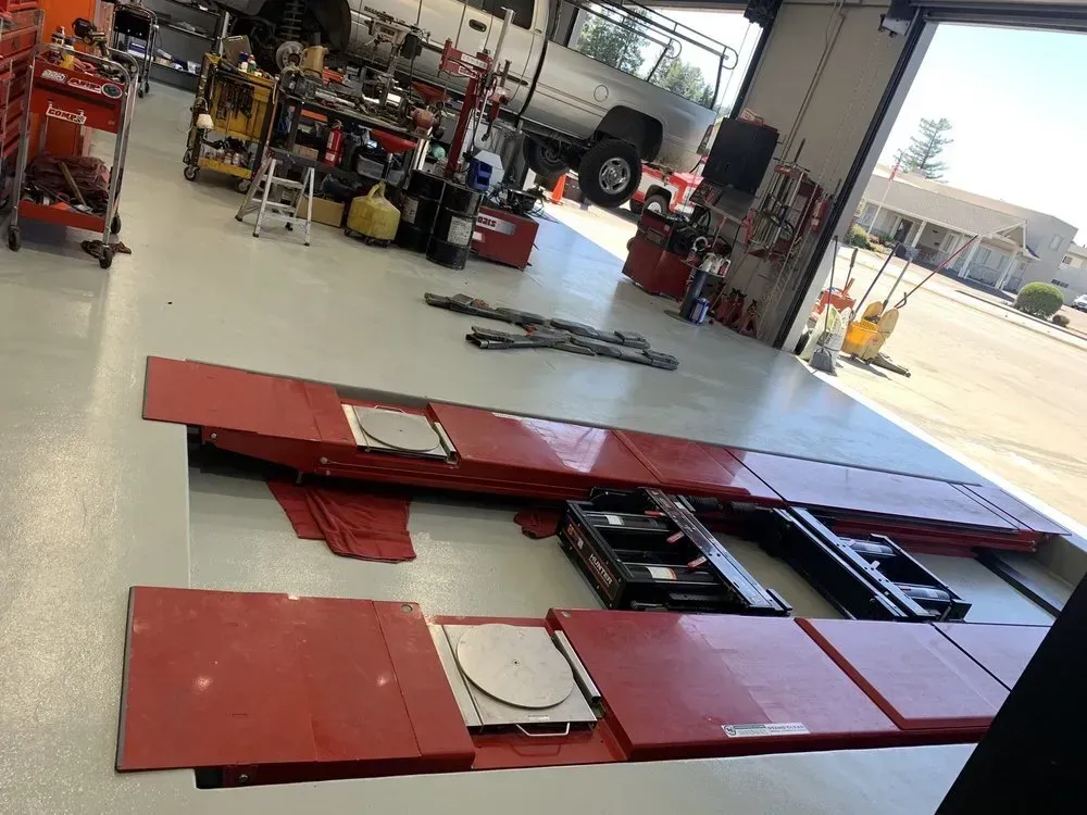 Interior of a garage with a red lift system on a bright floor, and tools.