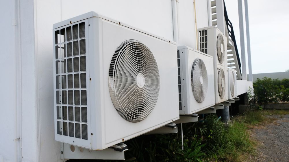 White Air Conditioning Units Mounted on a White Wall Outdoors — Les Carman Cooling Solutions in Innisfail, QLD