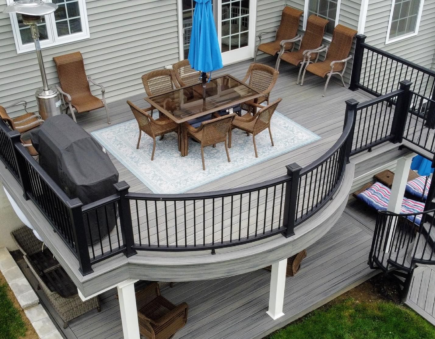 Outdoor deck with dining table, chairs, and grill, overlooking a yard.