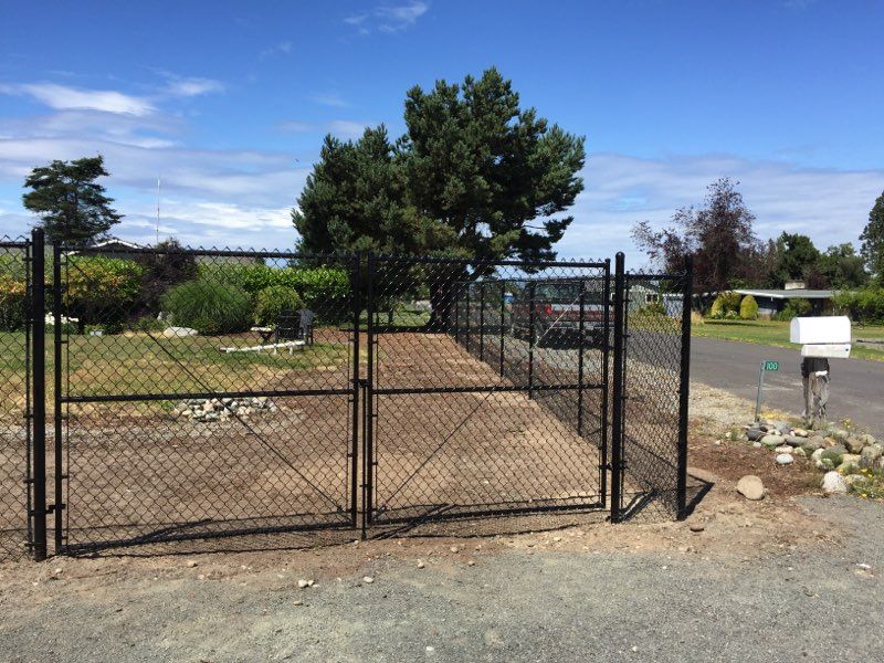 A Black Chain Link Fence Surrounds a Dirt Road - Sequim, WA- NW Chainlink Fence Co