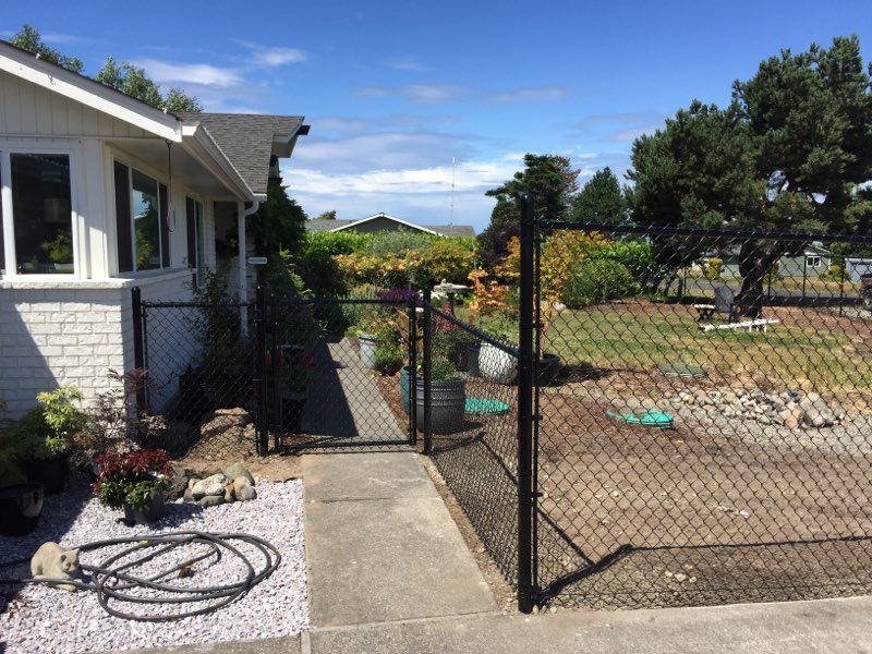 A Black Chain Link Fence Surrounds a White House - Sequim, WA- NW Chainlink Fence Co