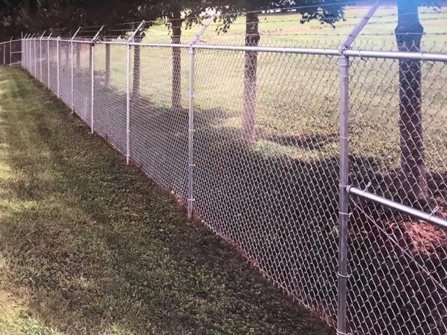 A Chain Link Fence Is Surrounded by Grass and Barbed Wire - Sequim, WA- NW Chainlink Fence Co