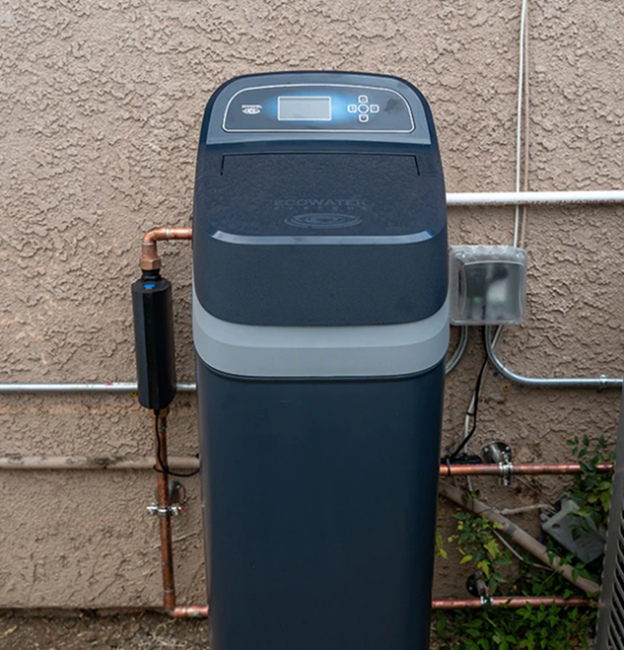 A water softener system with a control panel and copper pipes installed against a textured wall