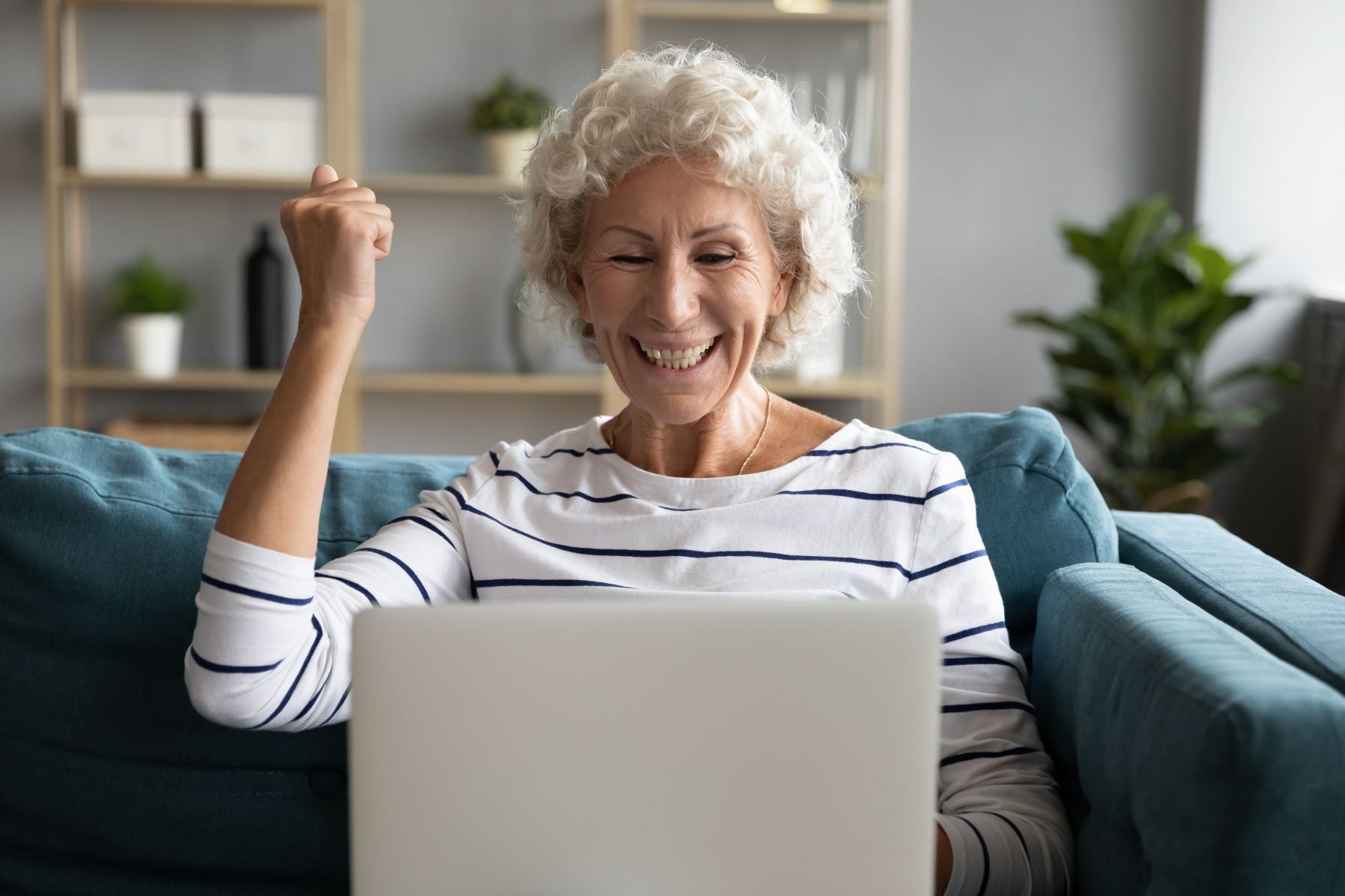 An Elderly Woman is Sitting on a Couch Using a Laptop Computer — NH Legal In South Nowra, NSW