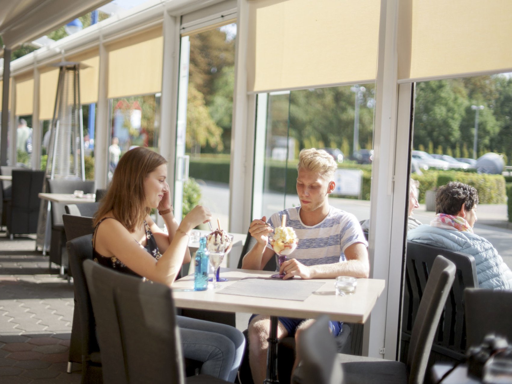 Zwei Personen essen Eis an einem Tisch am Fenster in einem Restaurant.