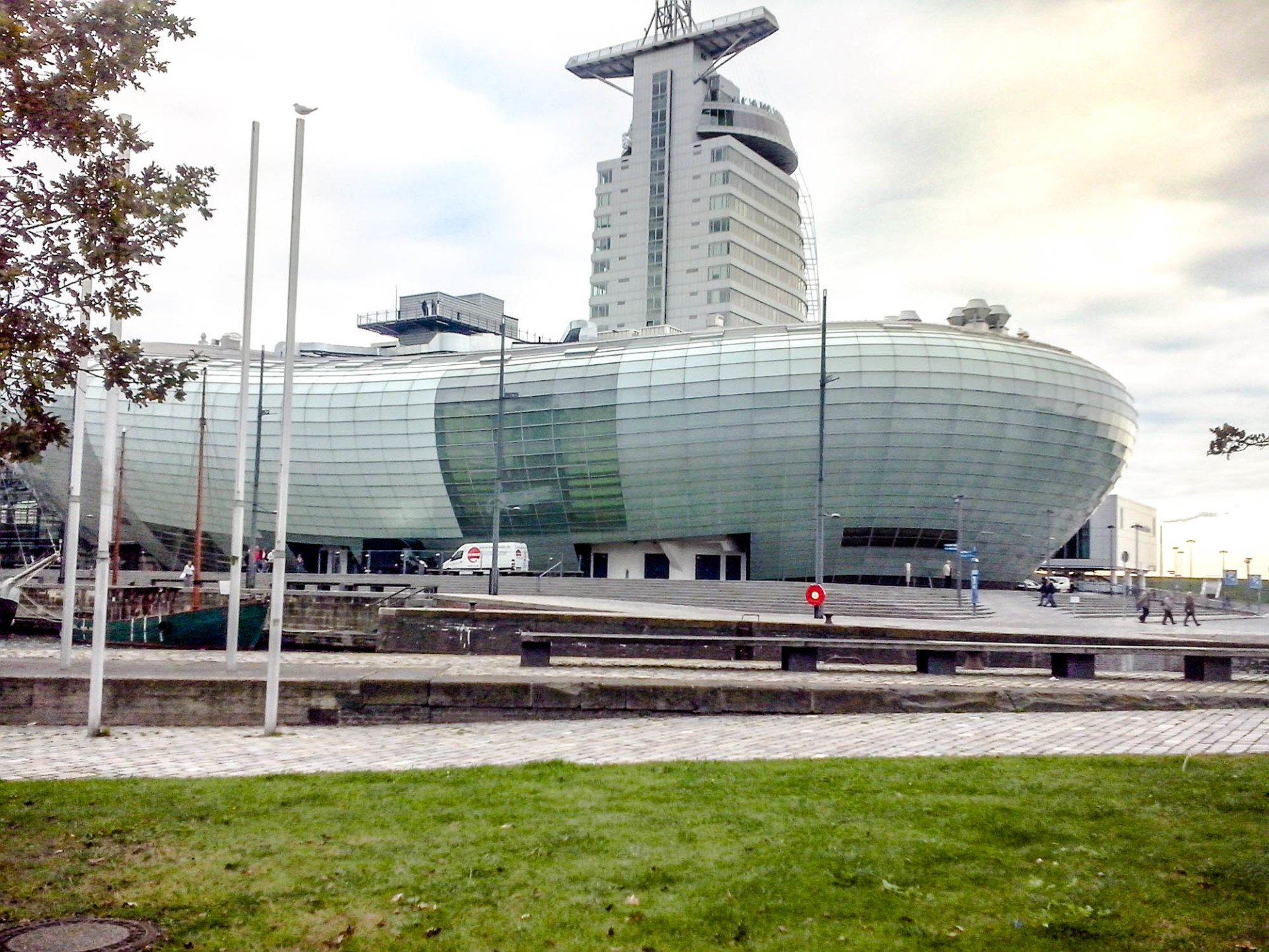 Ein modernes Gebäude mit geschwungener Glasfassade und einem hohen Turm.