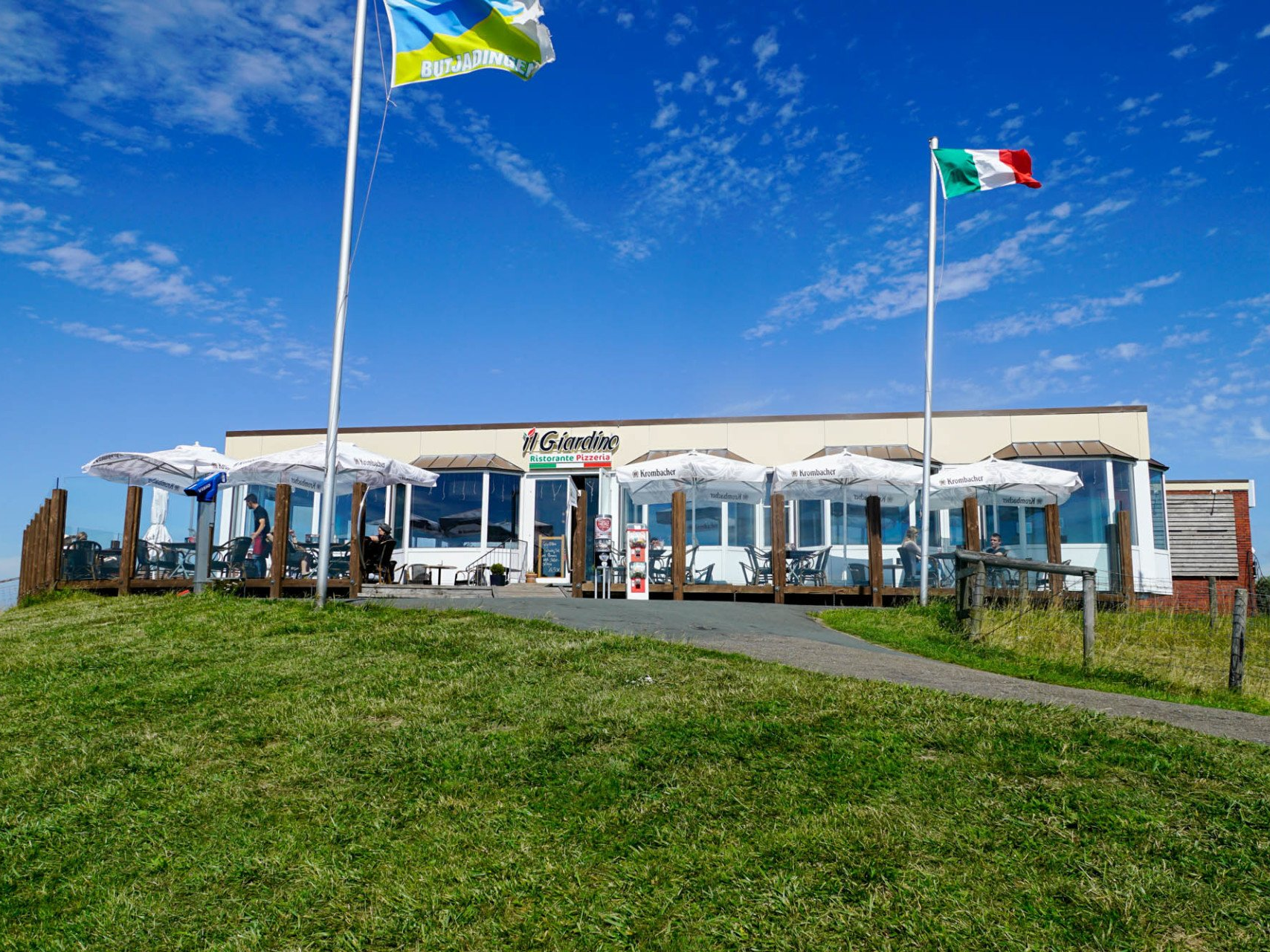 Restaurant „Il Giardino“ mit ukrainischen und italienischen Flaggen unter blauem Himmel.