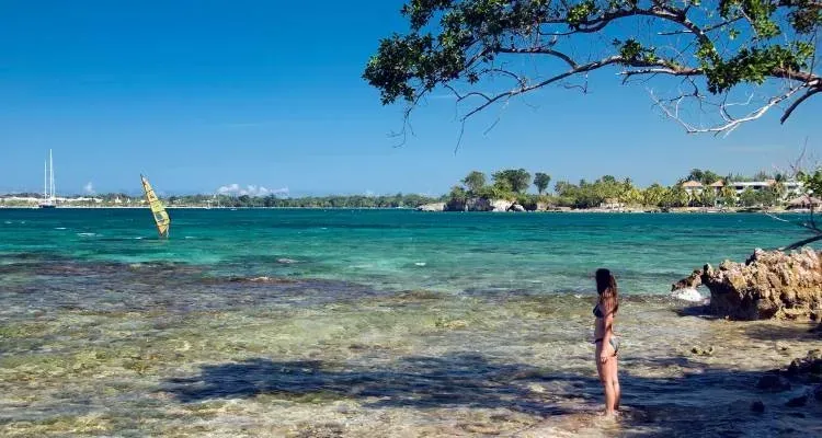 A woman is standing on a beach looking at the ocean.