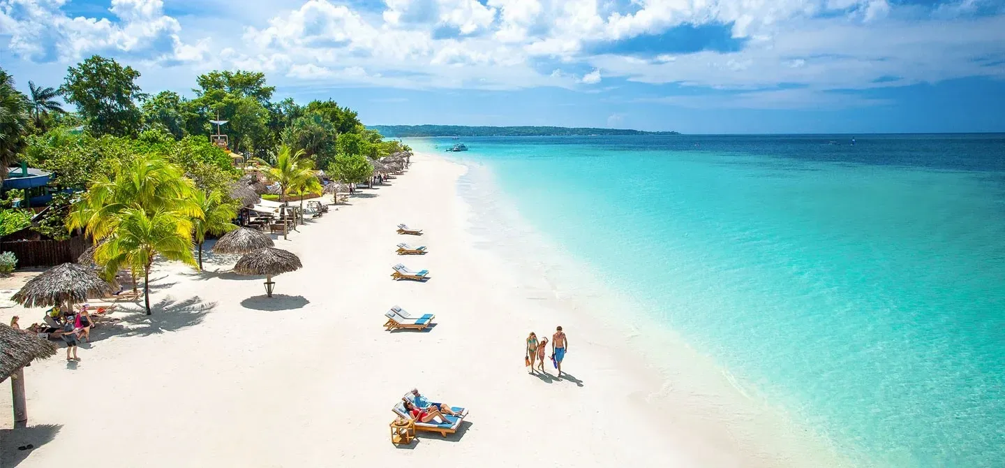 An aerial view of a tropical beach with people and umbrellas.