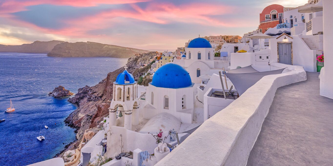 A row of white buildings on a hill overlooking the ocean.