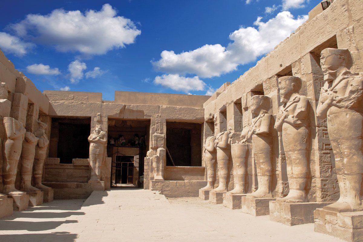 A row of statues are lined up in front of a building.