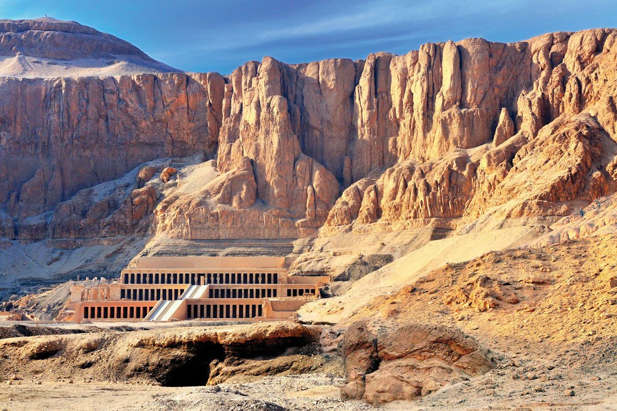 A large building in the middle of a desert surrounded by mountains.