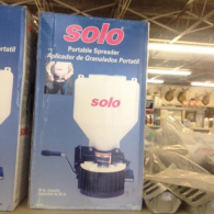 A Solo brand portable manual spreader in a blue box on a store shelf.