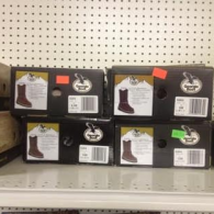 Four Georgia Boot shoeboxes stacked on a store shelf, each showing a picture of a brown boot on its label.