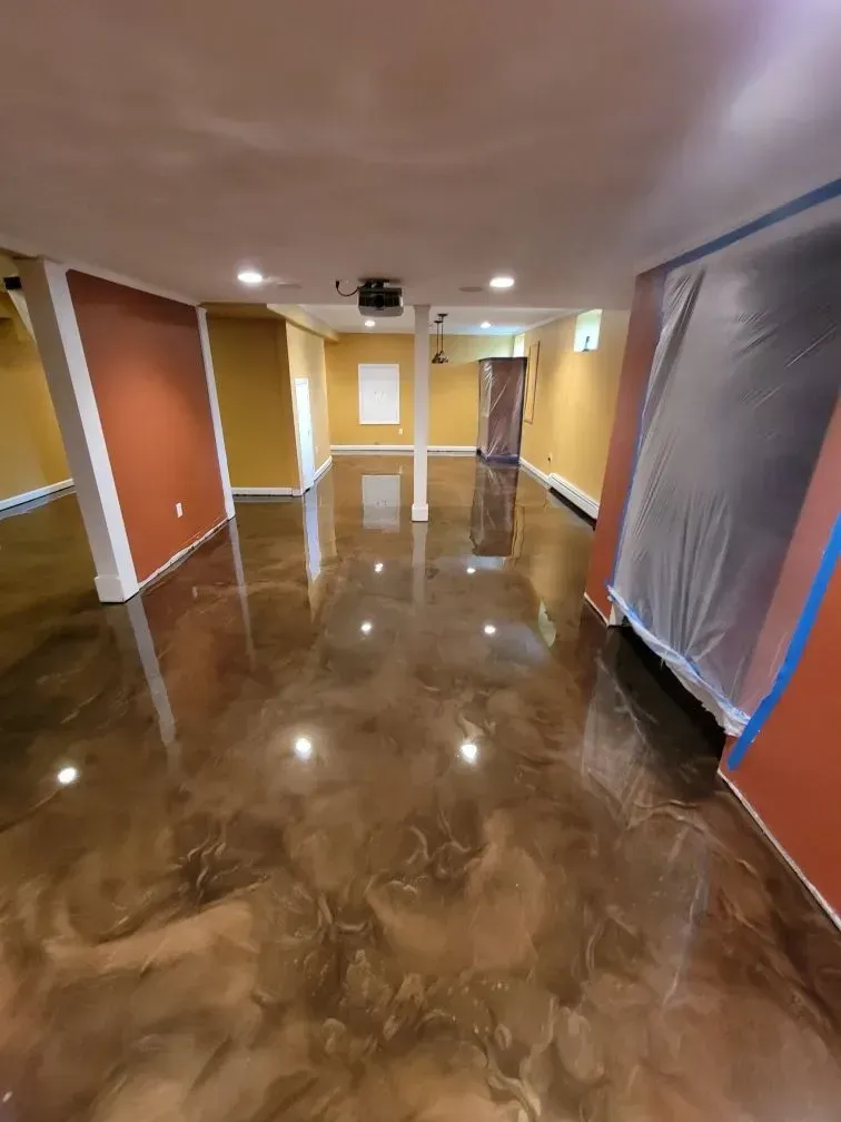 Room with metallic brown epoxy floor and colorful walls. White support columns.
