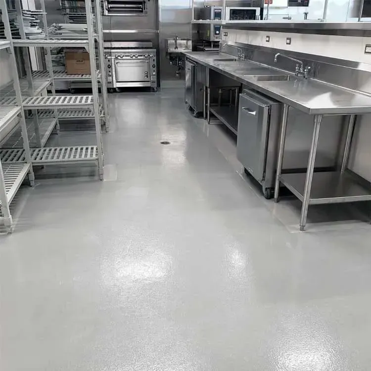 Empty commercial kitchen with stainless steel equipment and shiny gray floor.