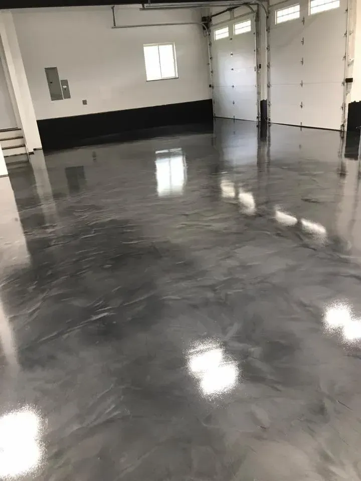 Shiny, metallic gray epoxy garage floor. Garage with white walls, window, and closed garage doors.