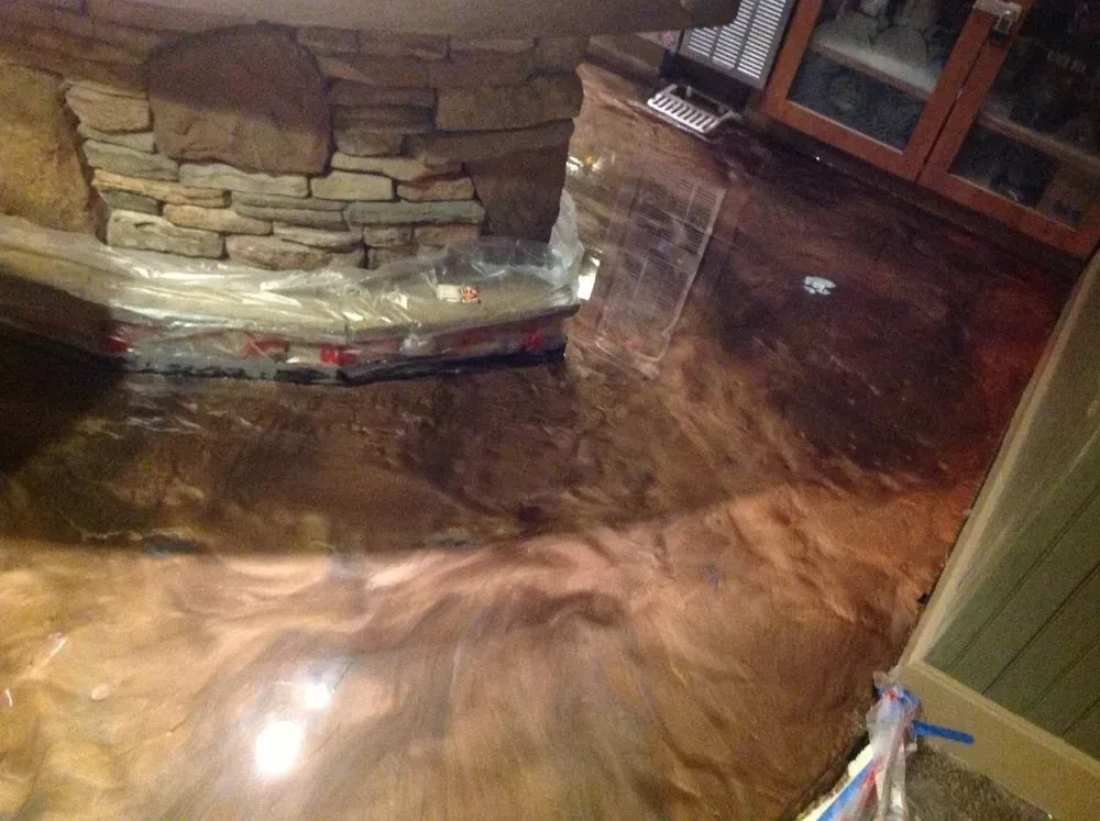 Metallic brown epoxy floor with swirling patterns near a stone fireplace.
