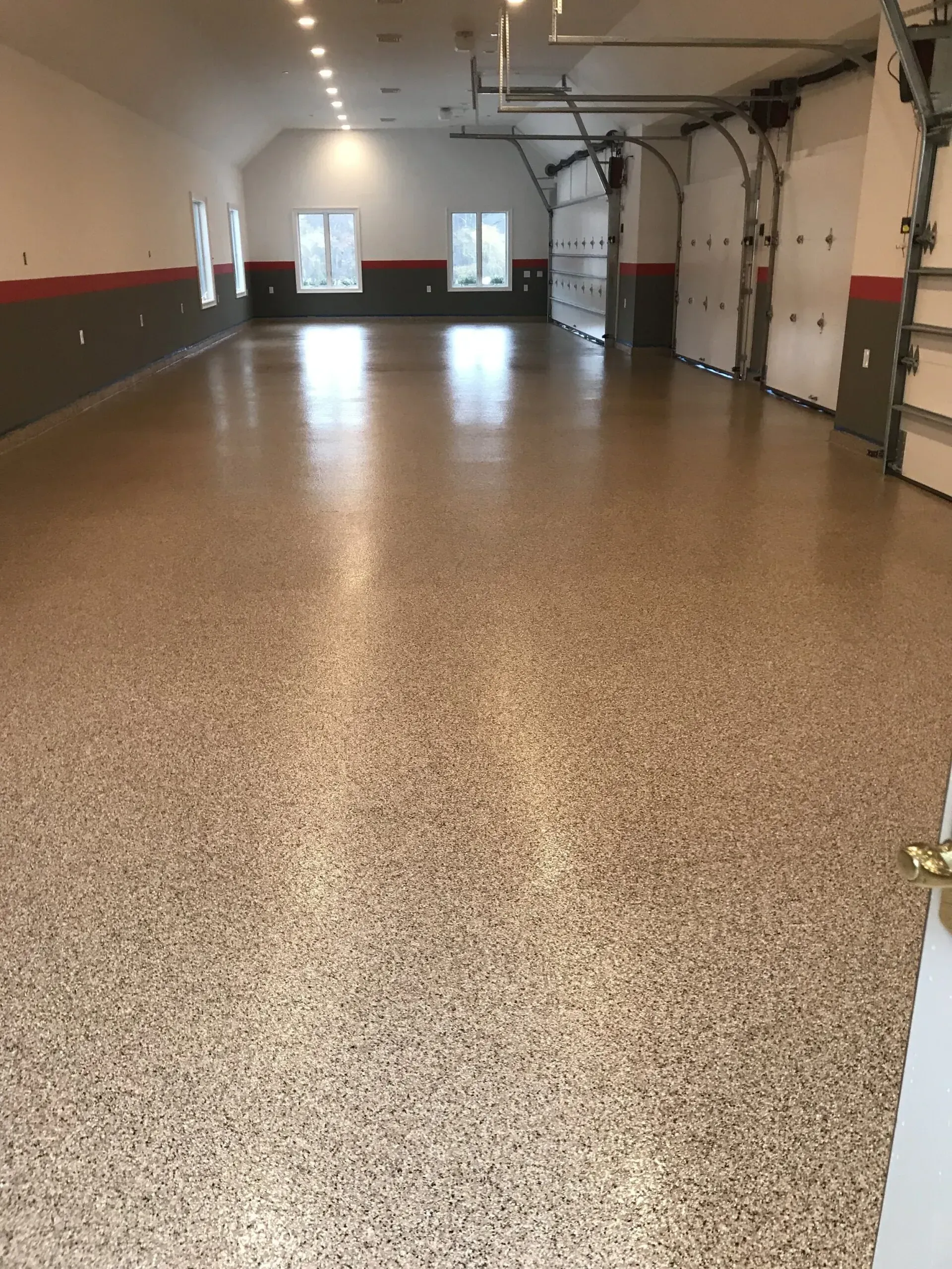 Spacious garage with a speckled epoxy floor, white walls, and three garage doors.
