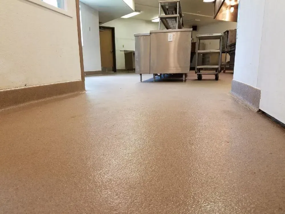 Commercial kitchen with beige floor, stainless steel equipment, and white walls.