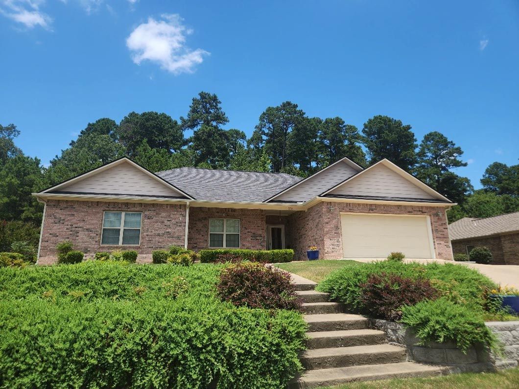 A brick house with a white garage door and stairs leading up to it.