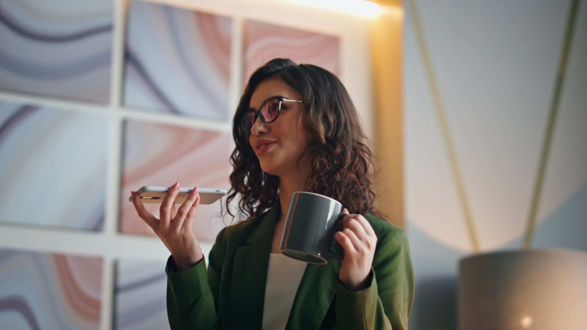 A woman is holding a cup of coffee and talking on a cell phone.