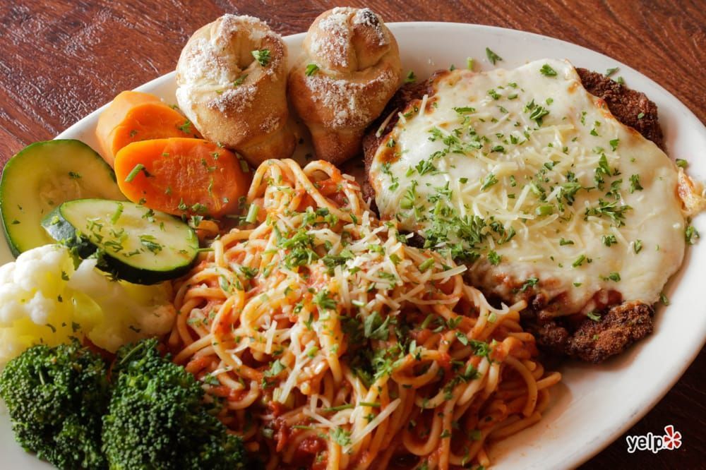 A white plate topped with spaghetti , meat and vegetables.