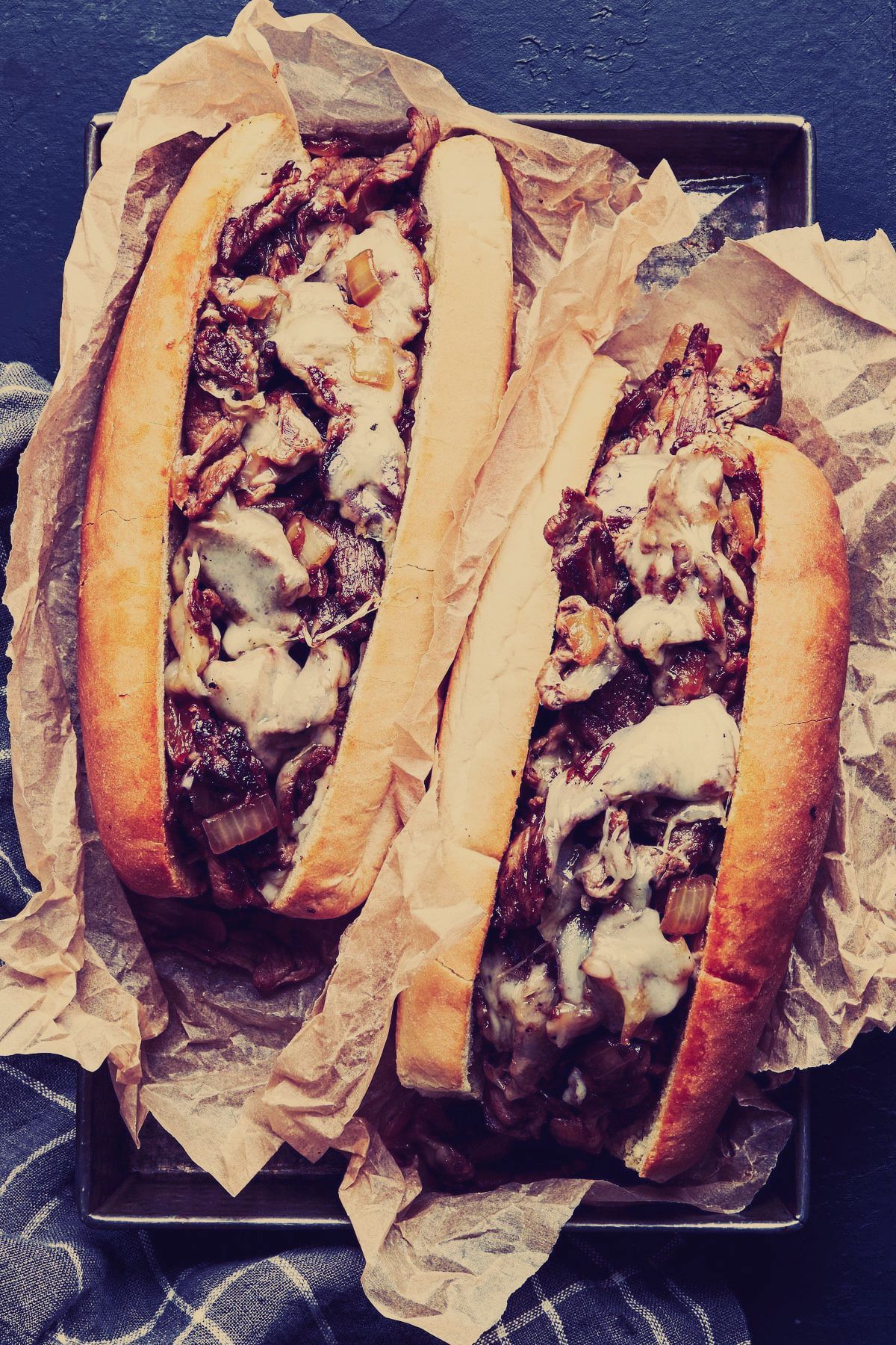 Two sandwiches are sitting on a piece of brown paper