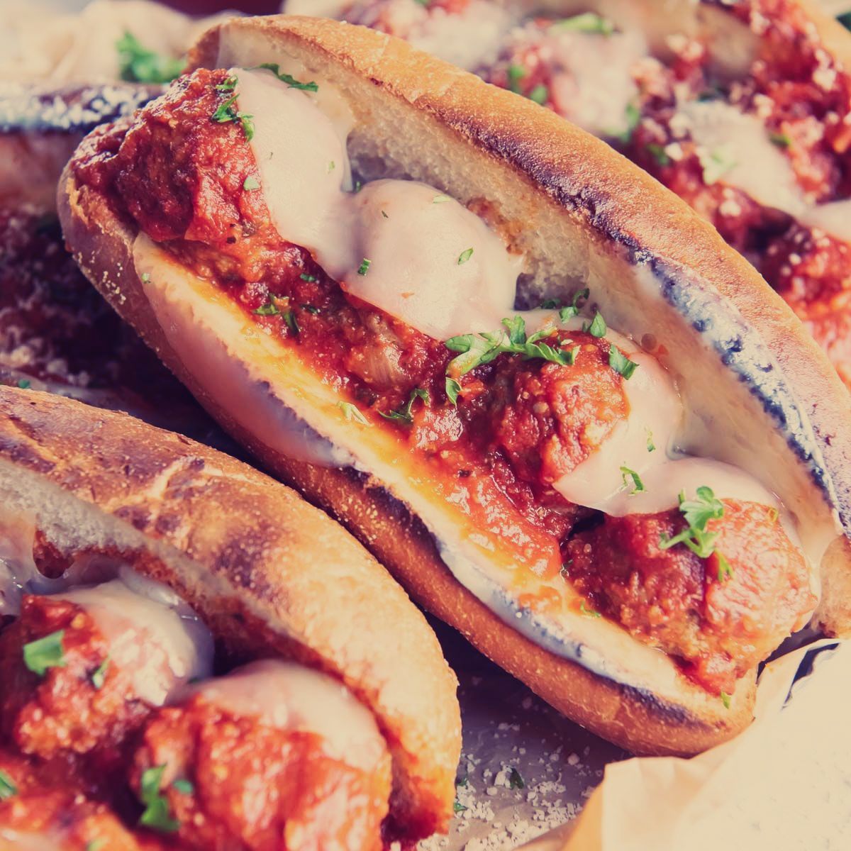 A bunch of sandwiches with meatballs and cheese on them