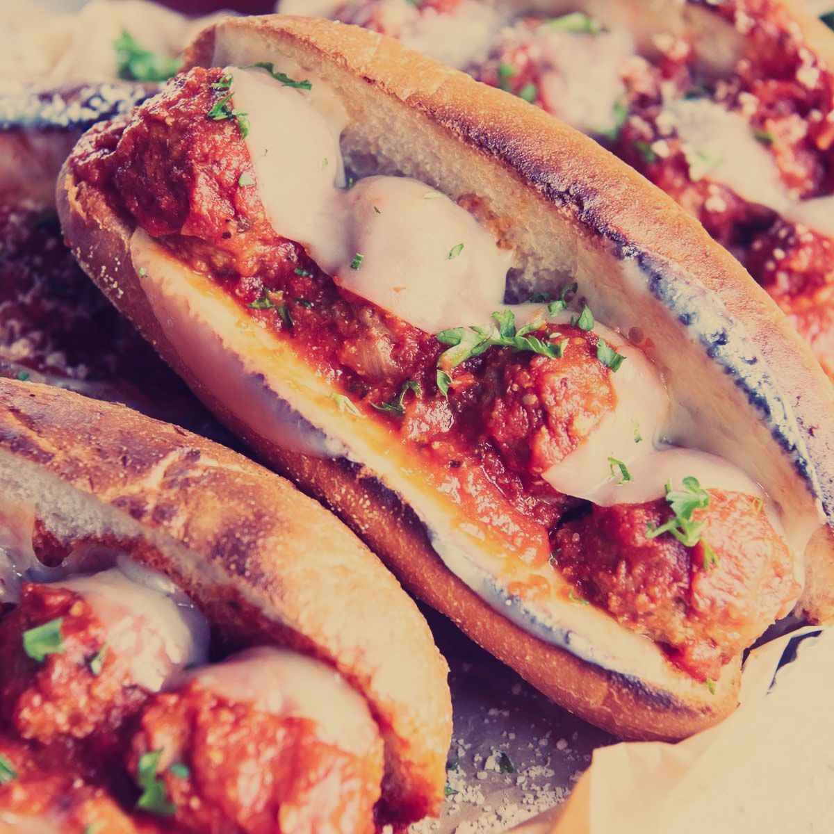 A bunch of sandwiches with meatballs and cheese on them