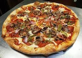 A pizza with pepperoni , mushrooms , onions and cheese is sitting on a metal table.