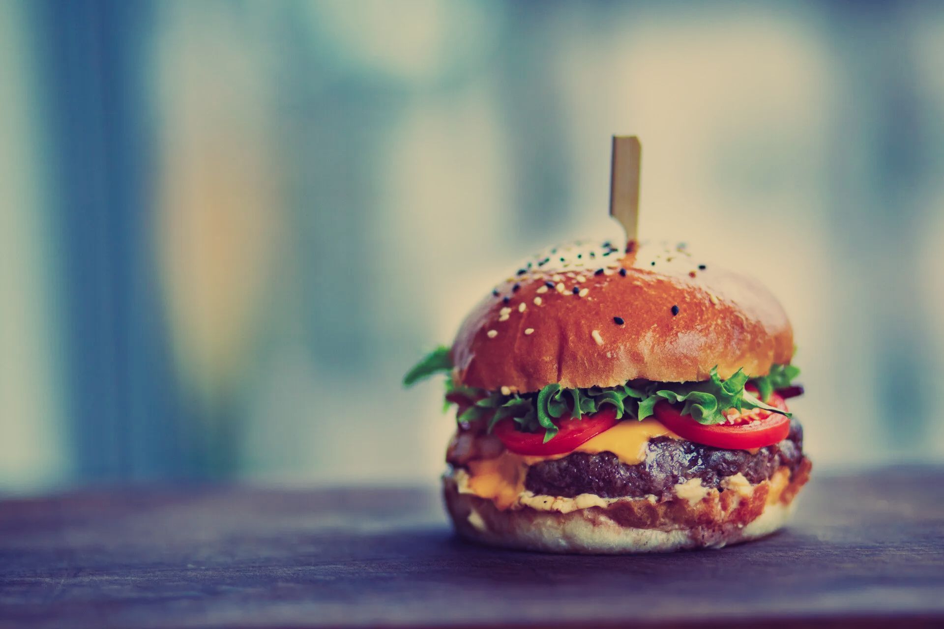 A close up of a hamburger on a wooden table.