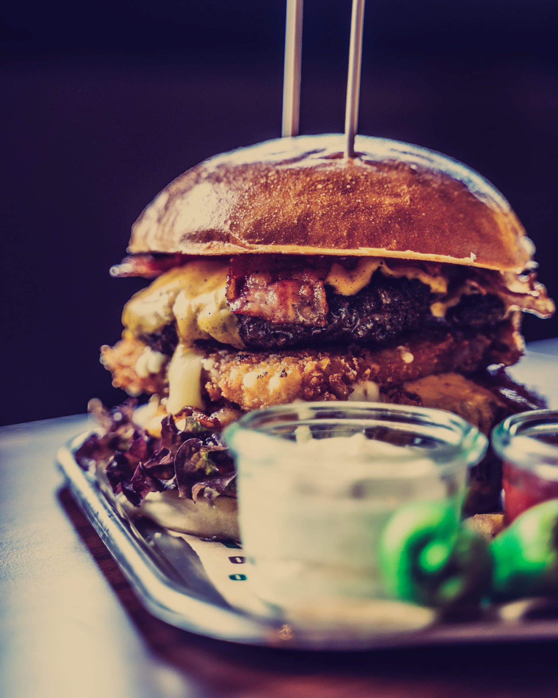 A close up of a hamburger on a tray with condiments
