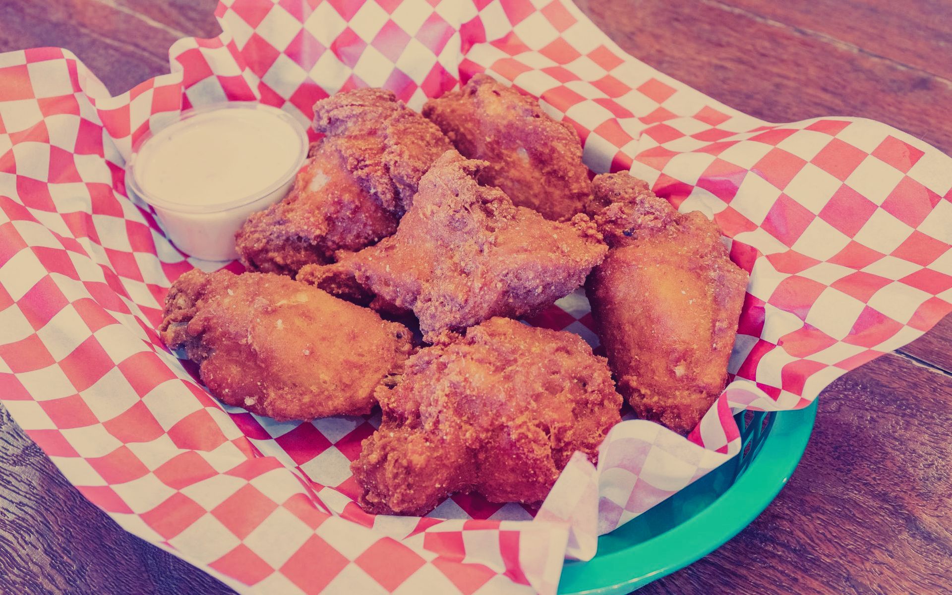 A green plate topped with fried chicken wings and dipping sauce.