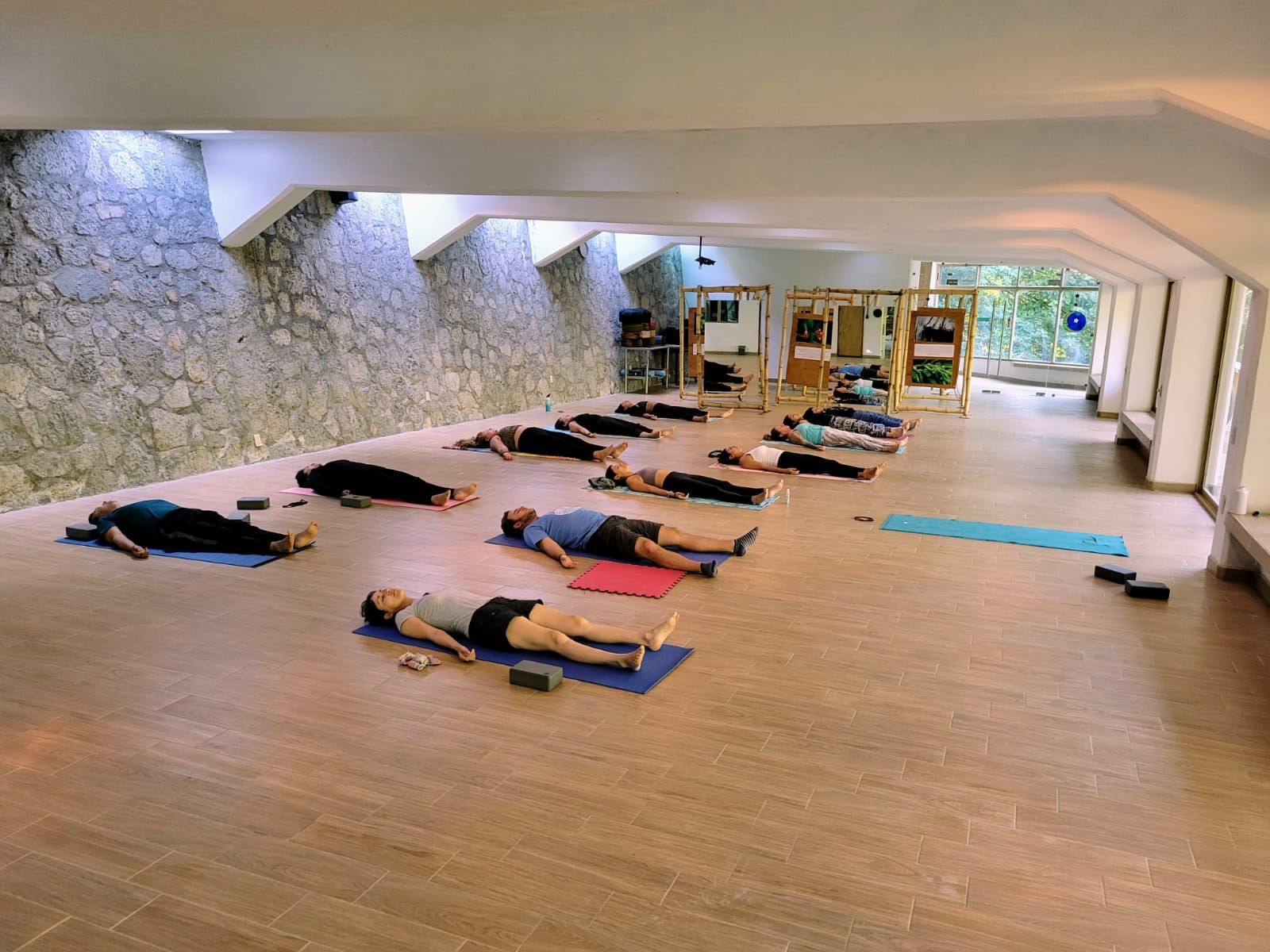 Un grupo de personas están acostadas sobre colchonetas de yoga en una sala grande.