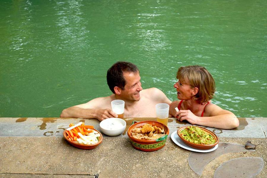 Un hombre y una mujer están en una piscina comiendo comida.