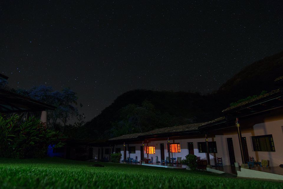 Una casa está iluminada por la noche con un cielo estrellado de fondo.