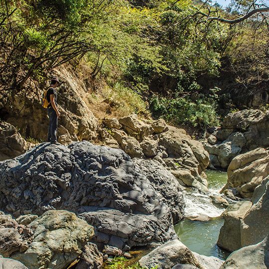 Un hombre está parado en la cima de una roca cerca de un río.