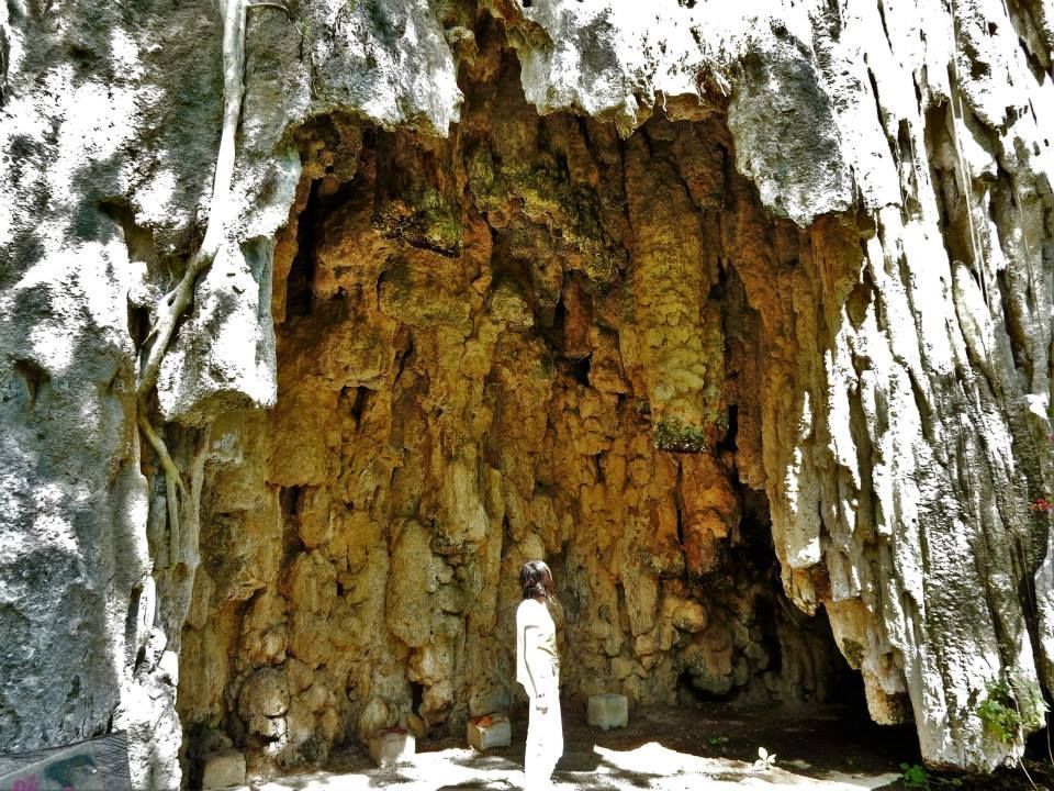 Una persona está parada frente a una gran cueva.